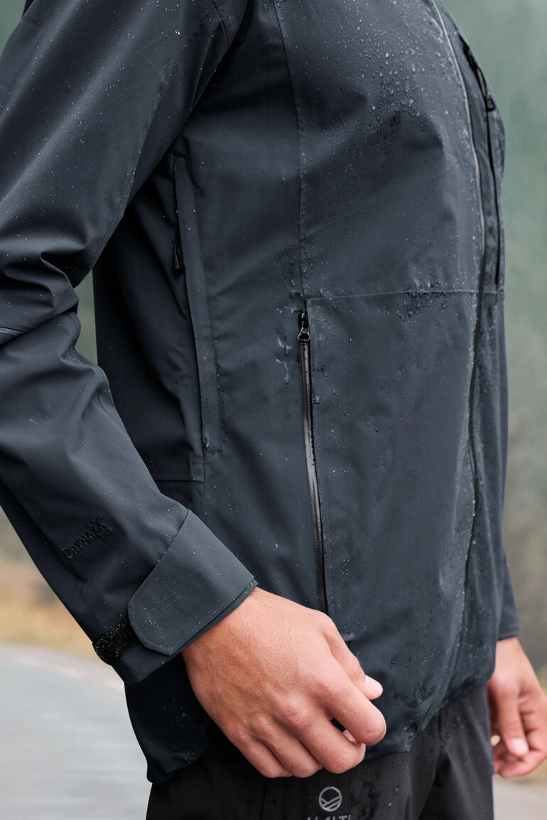 Seitenansicht der grauen Hardshell-Jacke mit sichtbar geschlossenen Reißverschlüssen.