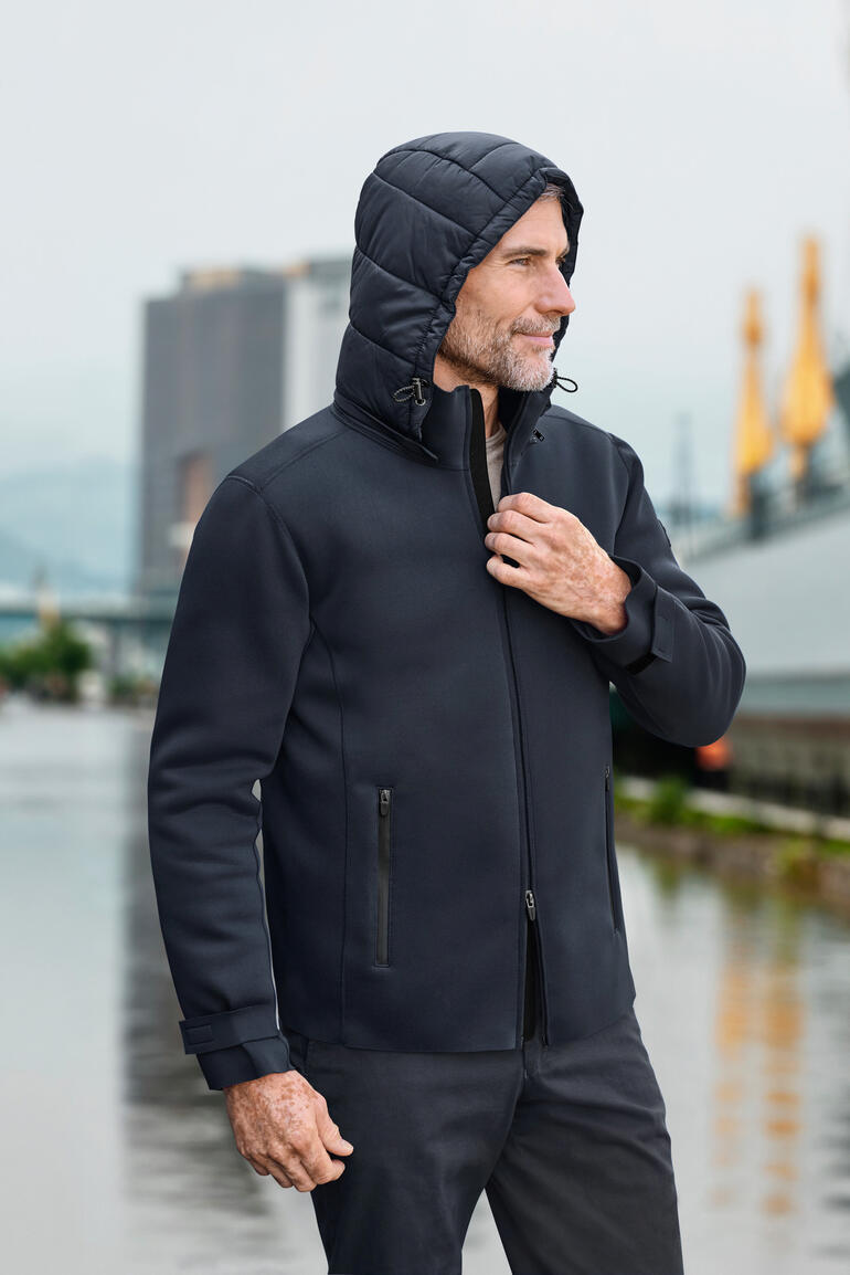 Mann in Neopren-Outdoorjacke mit Kapuze steht im Freien.