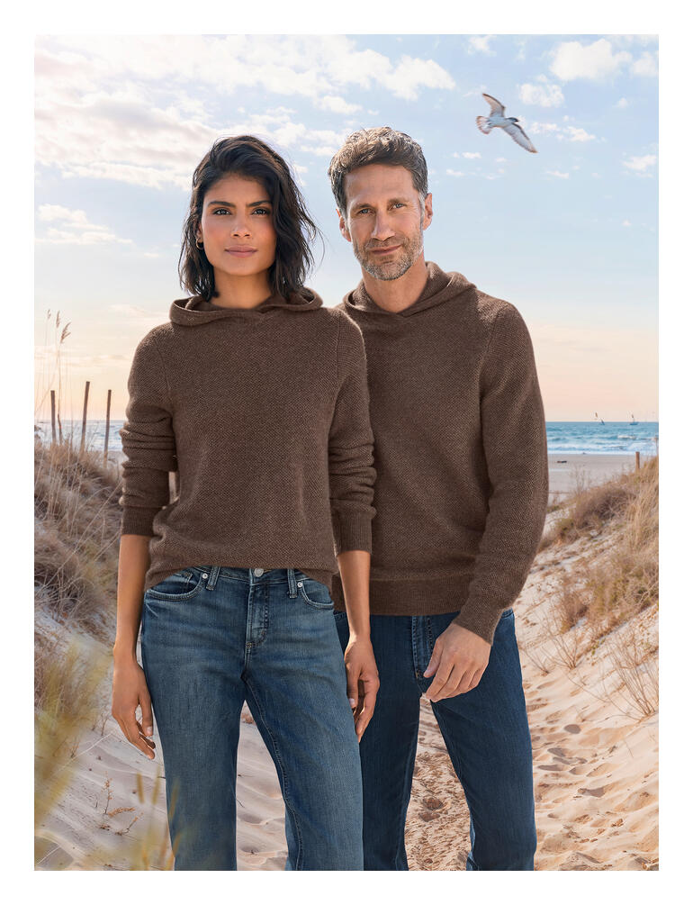 Paar im braunen JH1954 KA-Pique-Hoodie am Strand, mit Jeans bekleidet.