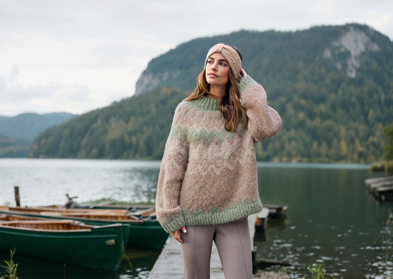 Baestmor Granny-Norweger-Pullover in Naturtönen, im Freien getragen vor einer malerischen Kulisse.