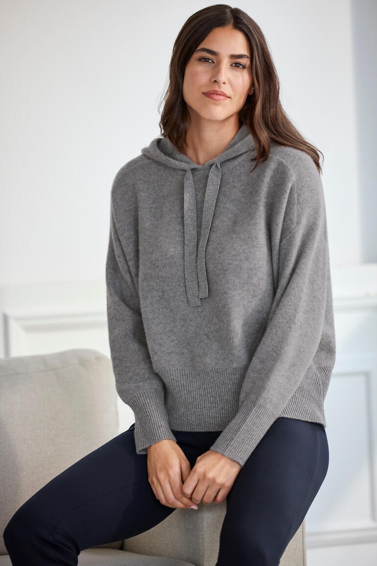Frau sitzt in grauem Boiled Cashmere D-Hoodie auf einem Sessel