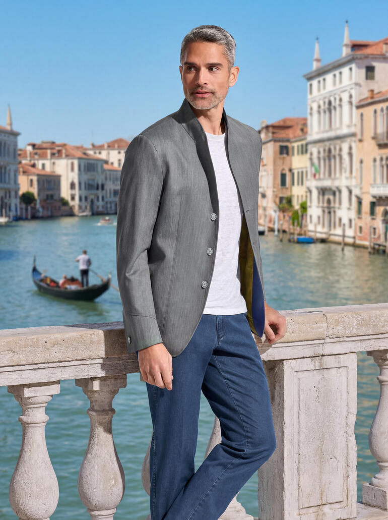 Mann in olivfarbenem Doubleface-Sakko vor venezianischem Kanal.