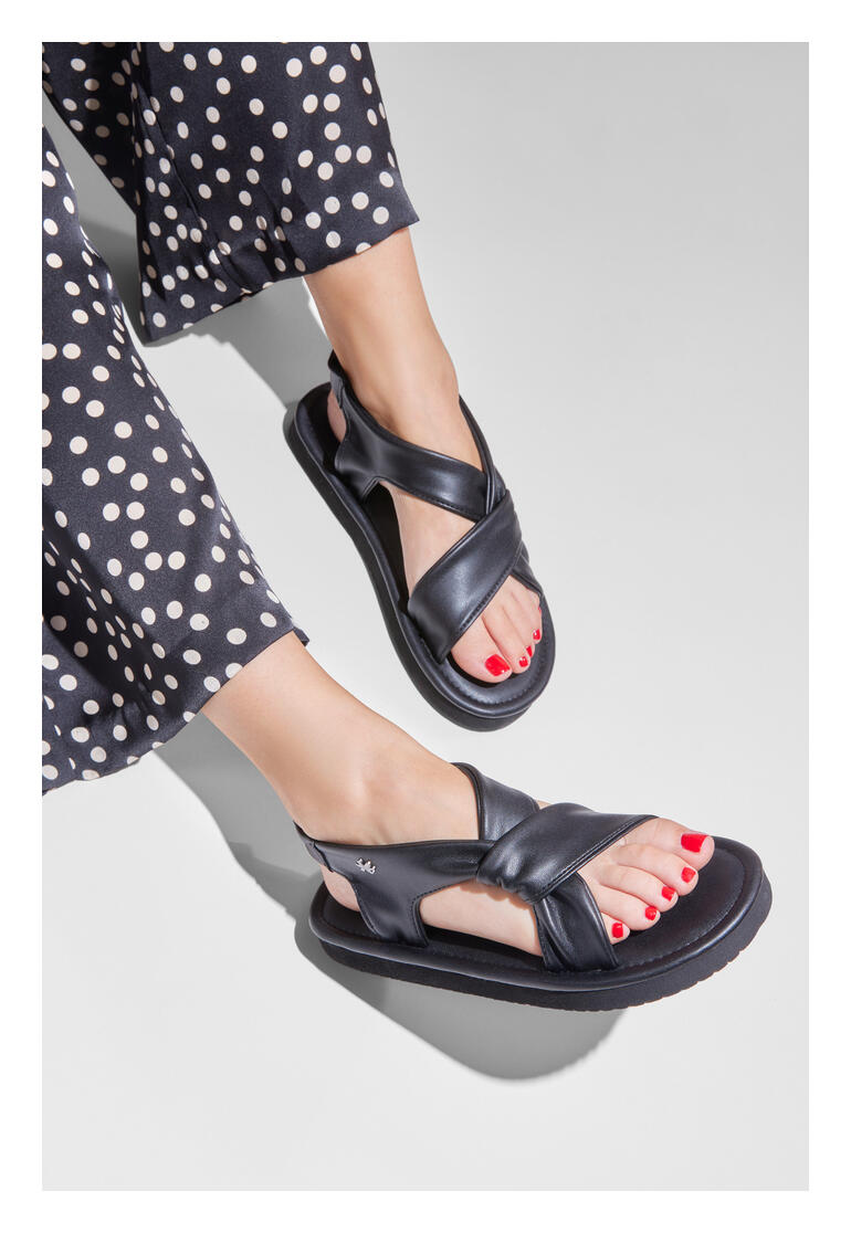 Füße einer Frau in schwarzen flip-flop Ultralight-Sandalen mit Nagellack