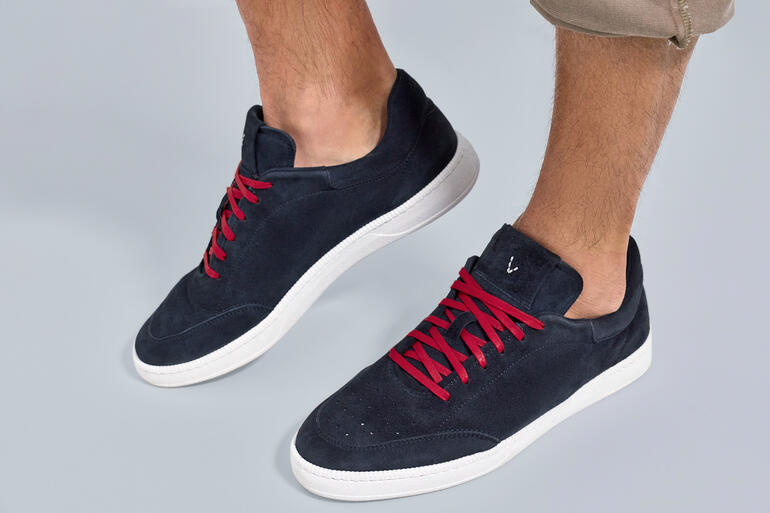 Navy-Sommersneaker mit roten Schnürsenkeln, steht auf einem grauen Untergrund.