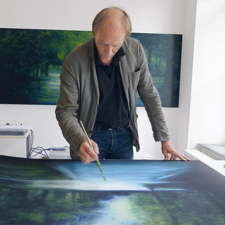 Erik Offermann arbeitet an einem großen Gemälde einer Parklandschaft.