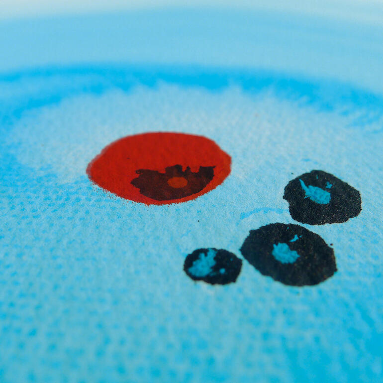 Nahaufnahme von blauen und roten Farbkreisen auf Aquarellpapier.