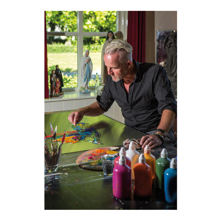 Paul la Poutré. Paul La Poutré beim Malen, umgeben von farbigen Farben und einer hellen Fensteransicht.