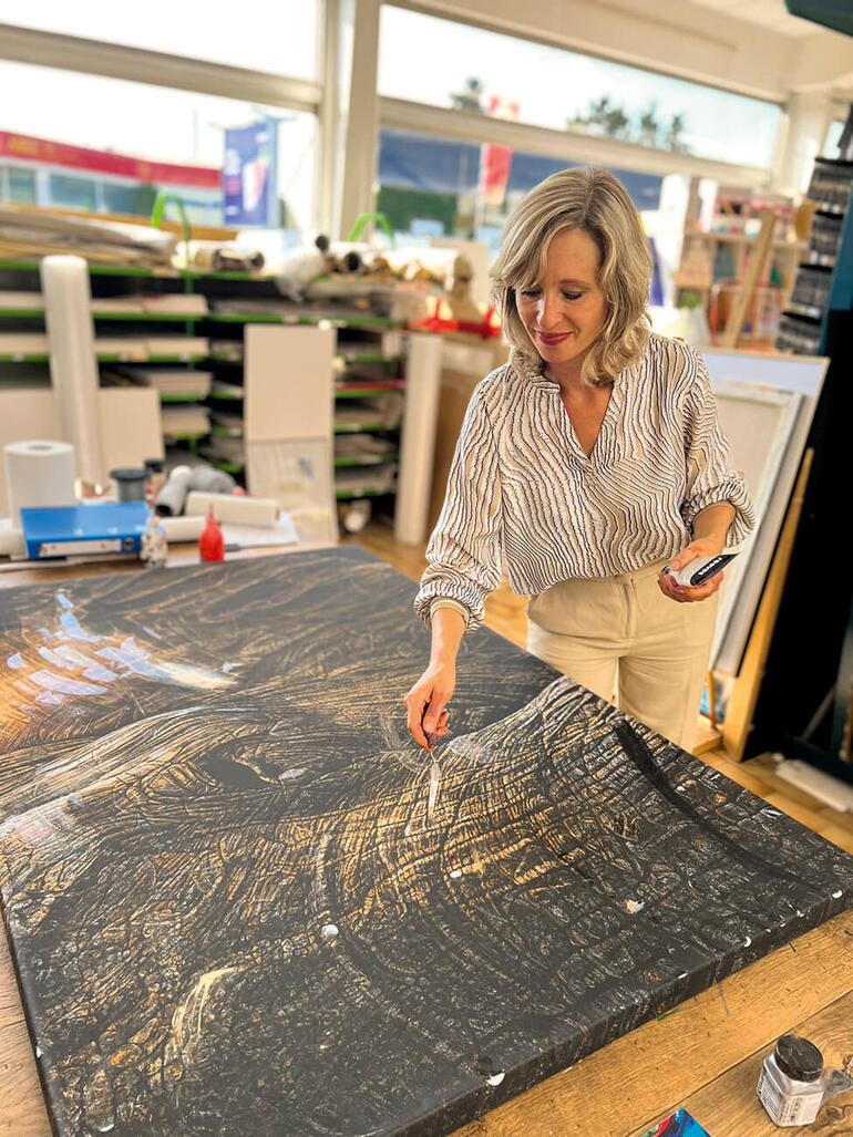 Künstlerin arbeitet an einem großen Elefantenkunstwerk in einem Atelier