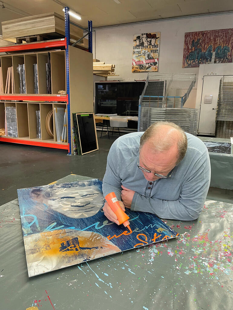 Mann arbeitet an einem Kunstwerk auf einem Tisch im Atelier.