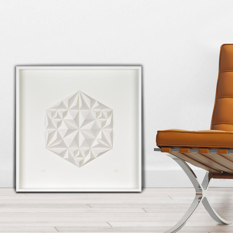 Geometrische Papierkunst in einem eleganten Rahmen neben einem Stuhl