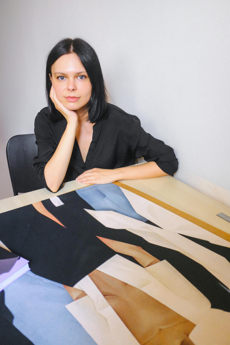 Künstlerin Valeriya Simantovskaya sitzt vor einem Tisch mit Kunstwerken.