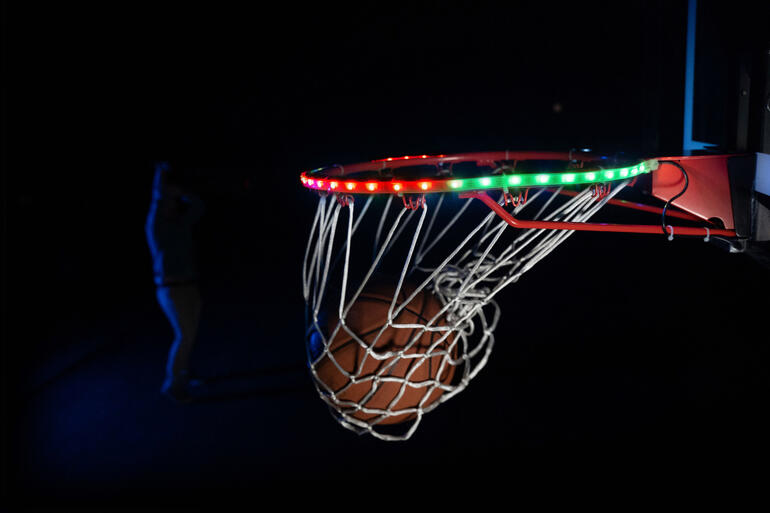 Nahaufnahme des Basketballkorbs mit LED-Leuchten und Ball in der Nähe.