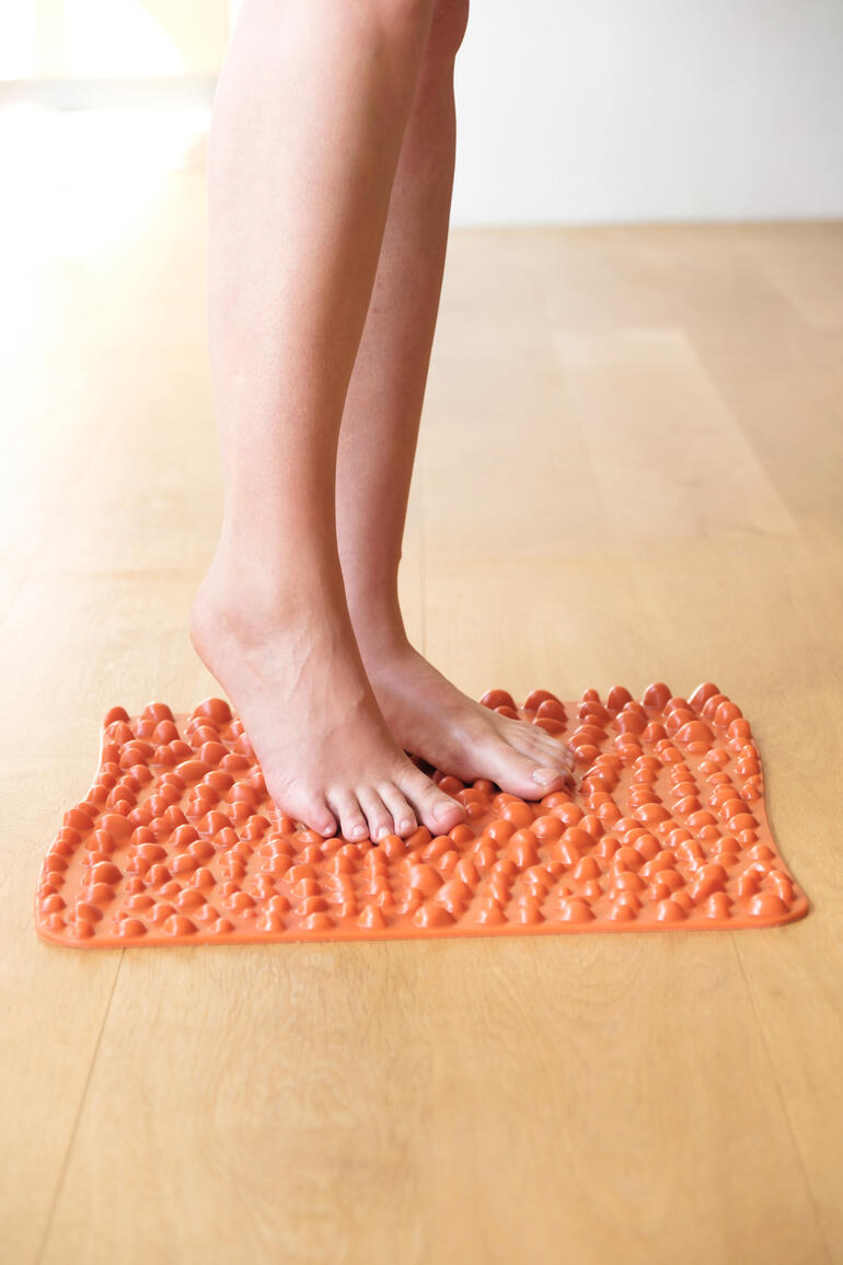 goFit-Fußreflexzonenmatte in leuchtendem Orange, Füße stehen darauf.