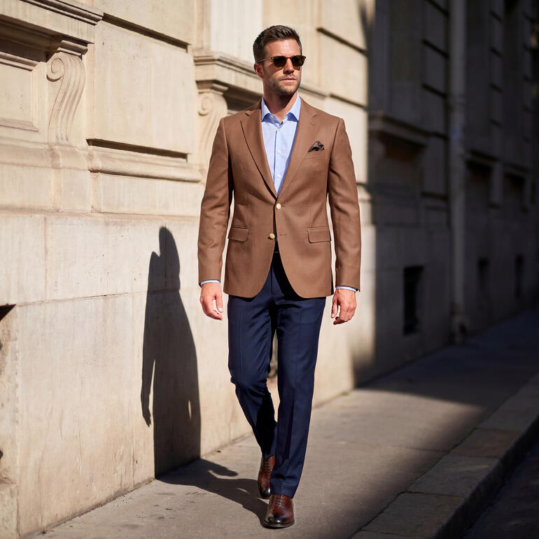 Mann im Carl Gross Hopsack-Blazer geht durch eine Stadtstraße.