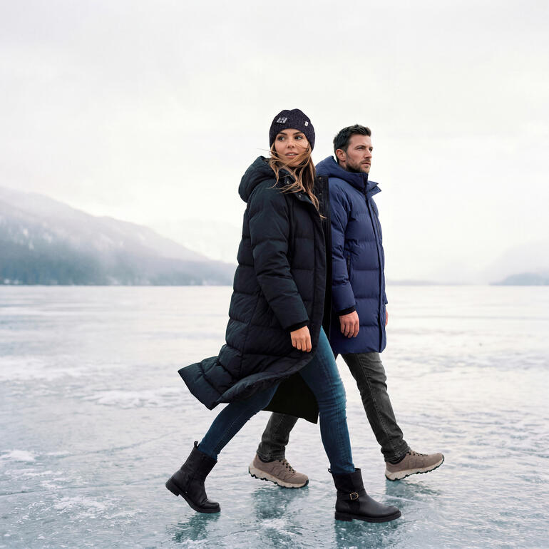 Paar trägt wasserdichte Puffer-Parkas auf einer gefrorenen Seenlandschaft
