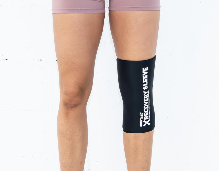 Frau trägt Kälte-/Wärme-Bandage am Knie