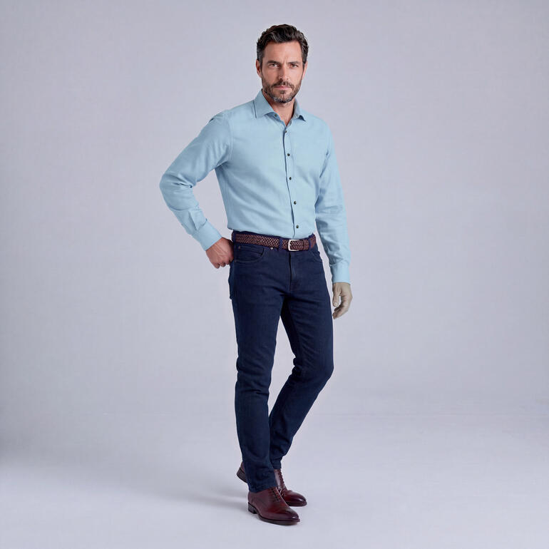Mann in Hemd und Jeans, posiert selbstbewusst.