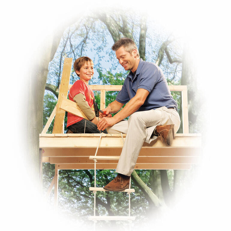 Vater und Sohn bauen zusammen eine Baumhütte.