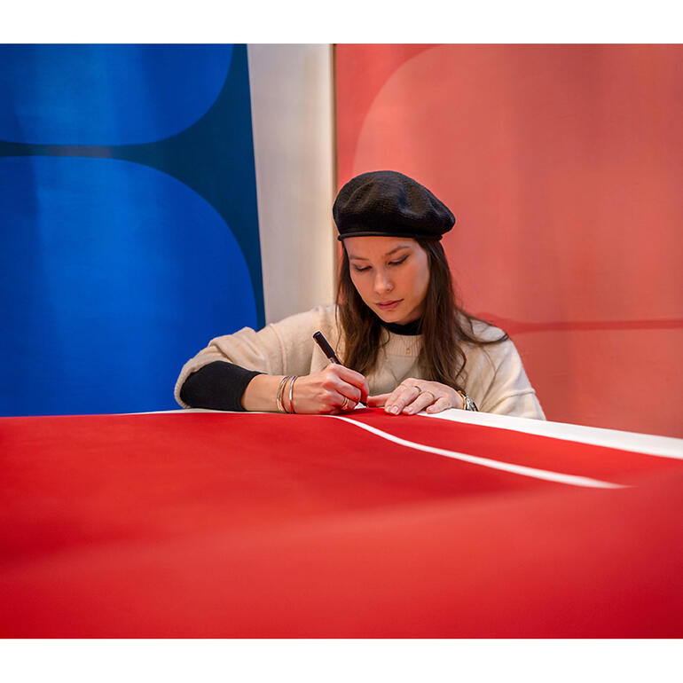 Lina Danitz Lina Danitz skizziert auf rotem Papier in einer kreativen Umgebung.