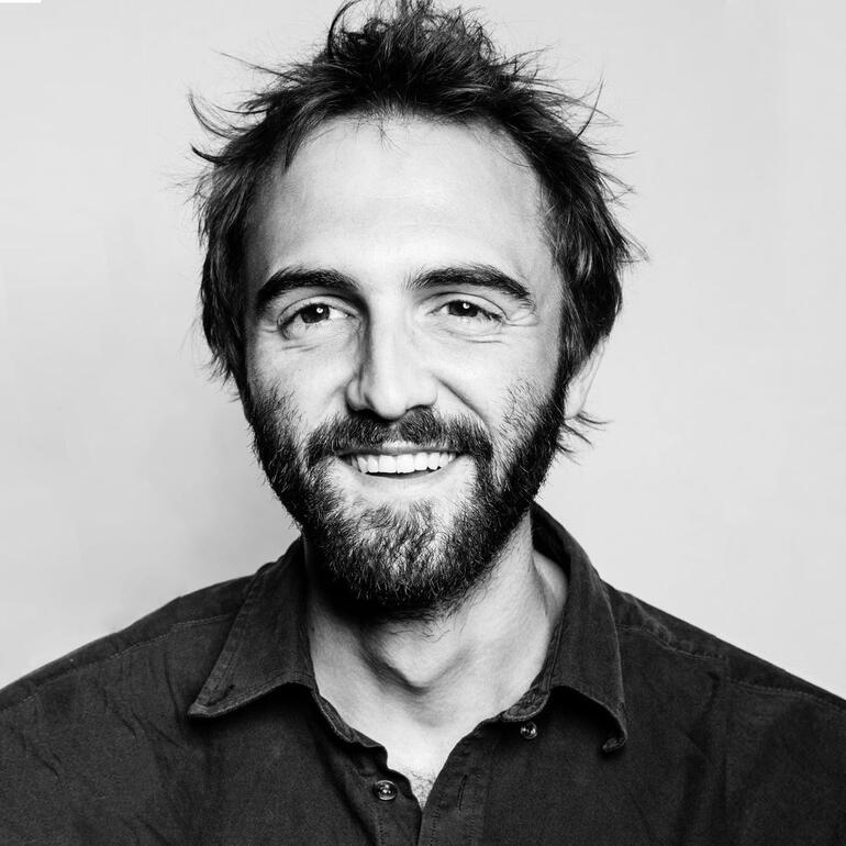 Marcel Teske lächelt in die Kamera in einem Schwarz-Weiß-Porträt.