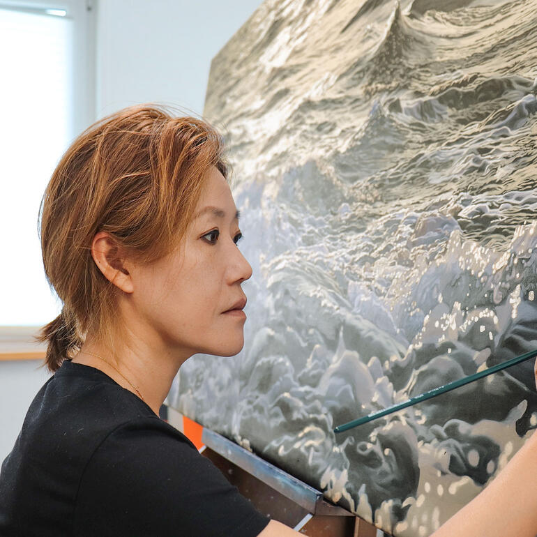 Eun Jung Seo-Zimmermann Eun Jung Seo-Zimmermann malt an einer großformatigen Welle.